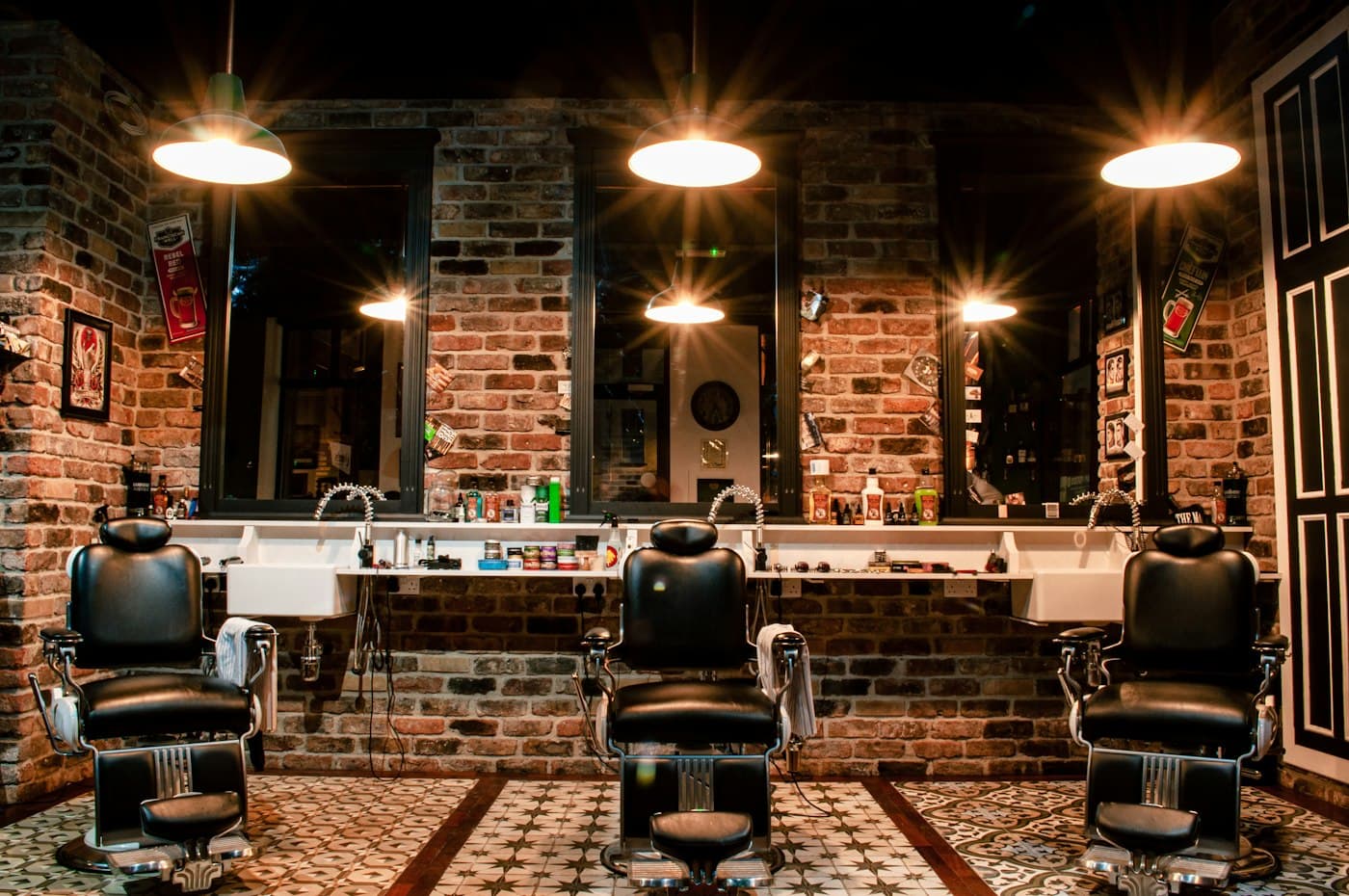 A barbershop interior with three barber chairs facing mirrors under warm lights.