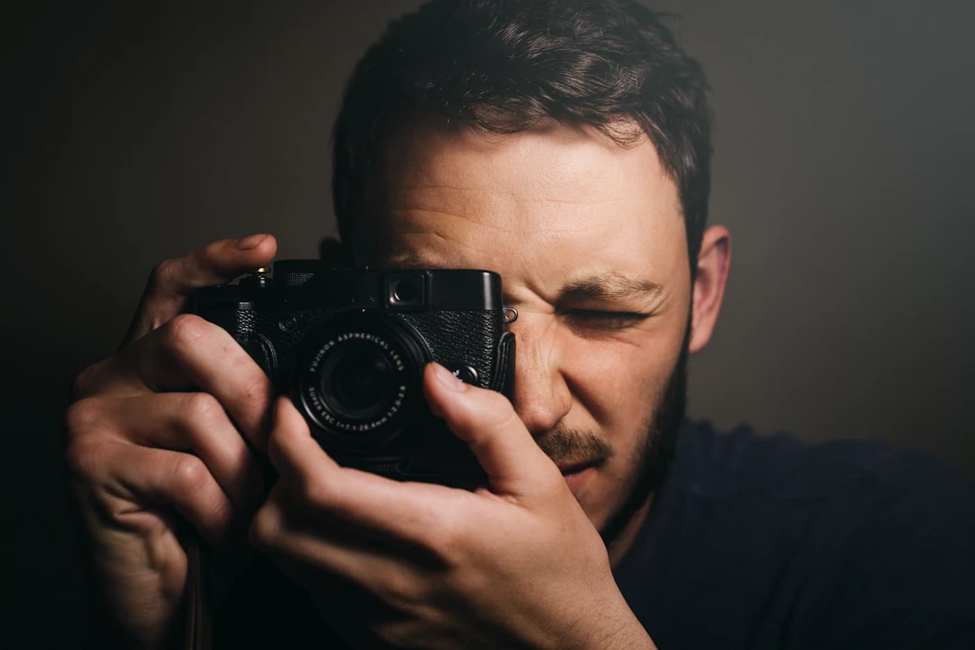 A photographer looking through the viewfinder of a black camera, ready to take a picture.